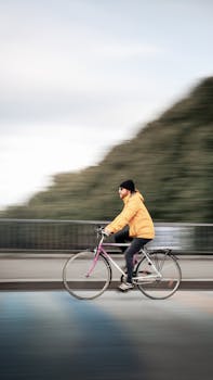 Person in a yellow jacket rides a bicycle across a bridge in Leipzig.