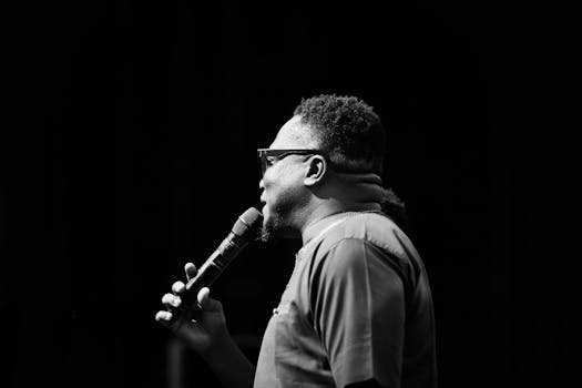 Side profile of a man with a microphone on stage captured in black and white.