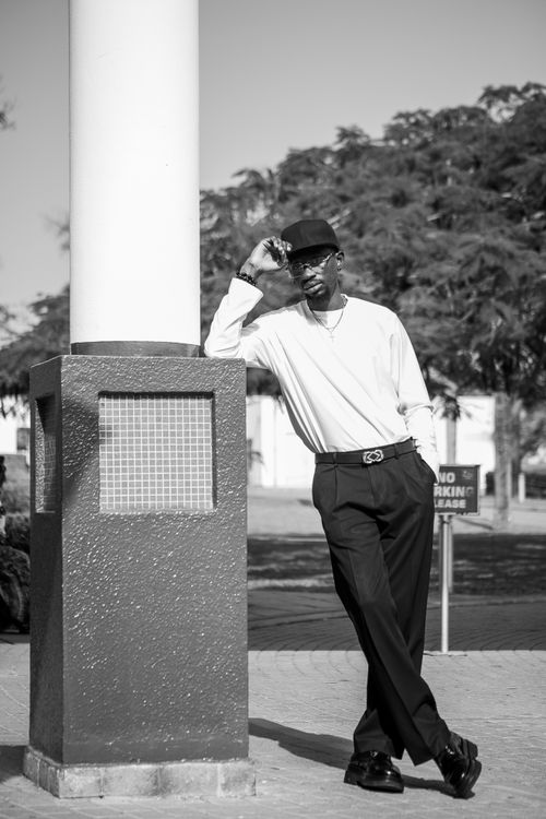 Free Monochrome photo of a fashionable man leaning on a column outdoors. Stock Photo