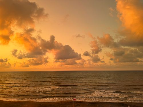 Free Breathtaking sunset over a serene ocean with vibrant orange skies and gentle waves. Stock Photo