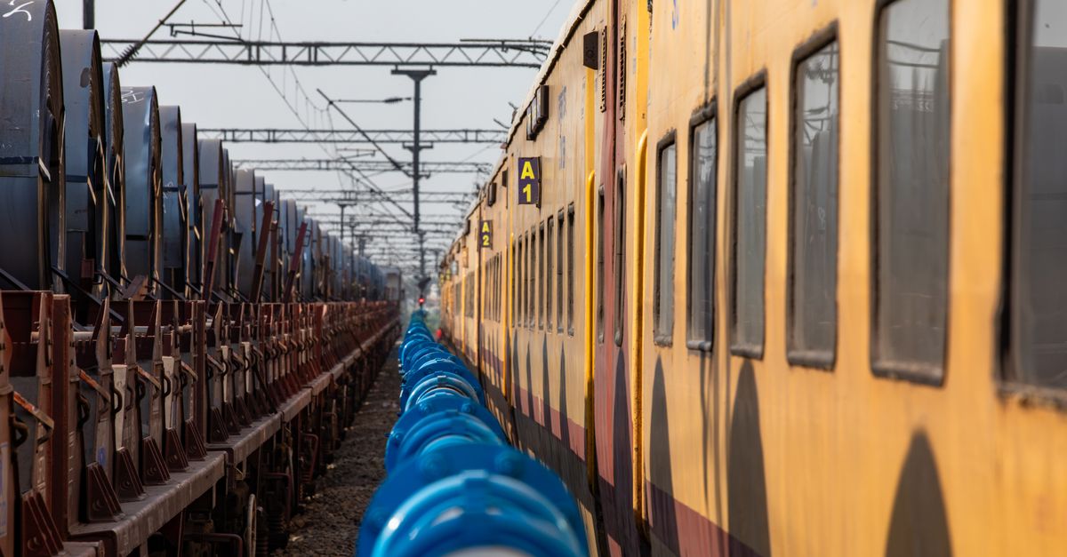 Parallel Train Parallel Trains and Blue Pipes on a Rail Yard · Free Stock Photo