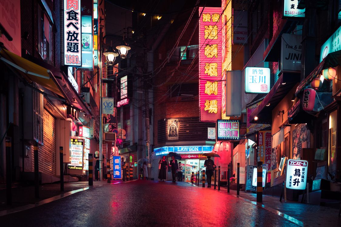 Vibrant neon lights illuminate a bustling Tokyo street at night