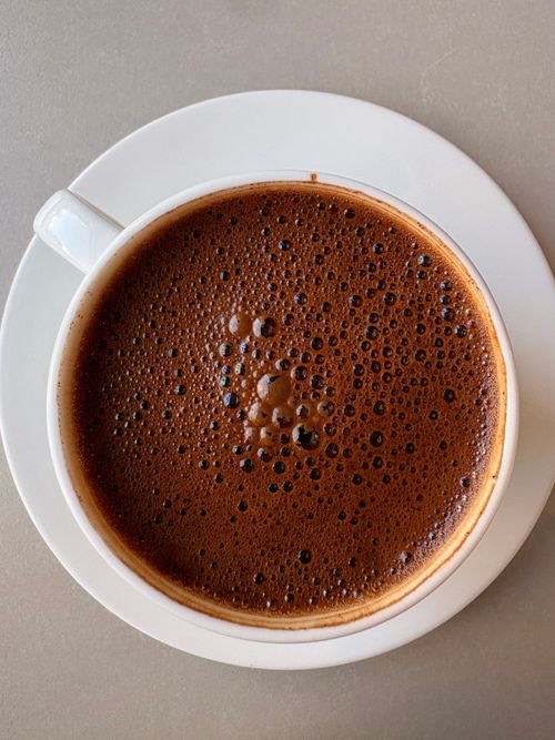 Free Aerial view of a frothy, rich coffee in a white cup on a saucer. Stock Photo