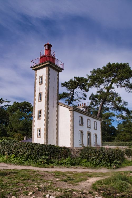 Free Majestic lighthouse surrounded by lush greenery under a vibrant sky in Bretagne. Stock Photo