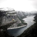 一名徒步旅行者以令人惊叹的挪威峡湾为背景，在特罗尔通加悬崖上欣赏着戏剧性的景色