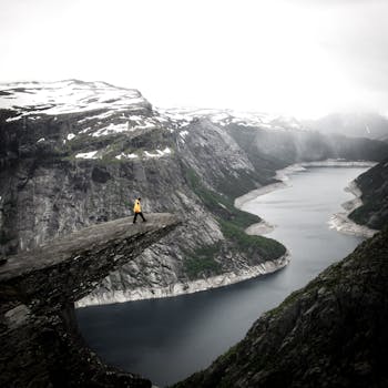 一名徒步旅行者以令人惊叹的挪威峡湾为背景，在特罗尔通加悬崖上欣赏着戏剧性的景色