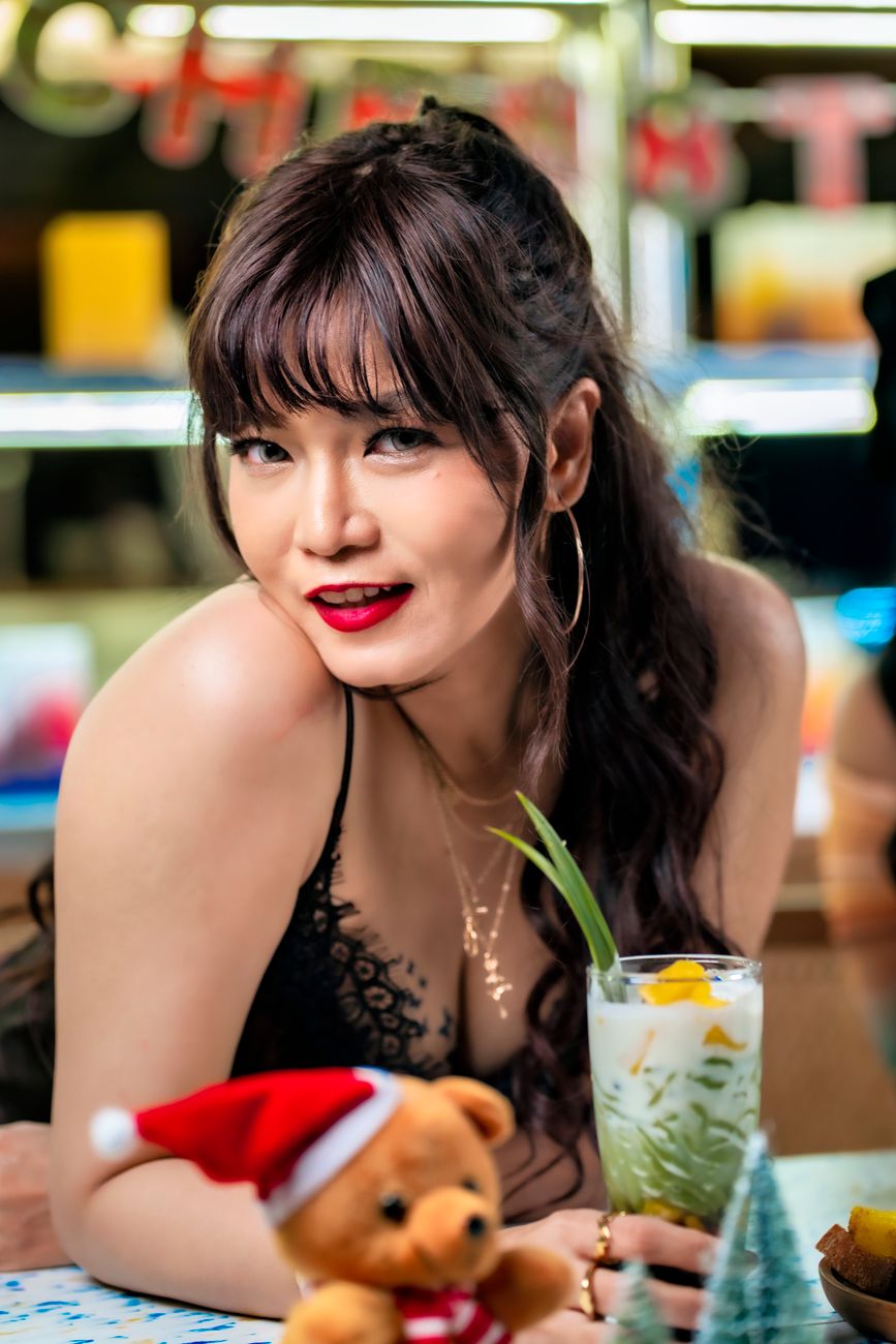 A woman enjoying a festive drink with Christmas decorations in Jakarta, Indonesia.