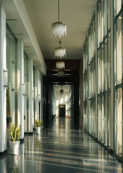 Sunlit modern corridor with large glass windows and chandeliers in Ho Chi Minh City, Vietnam.