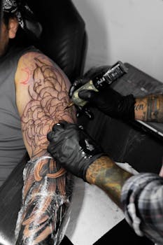Tattoo artist creating a detailed floral design on a client's arm in a studio.