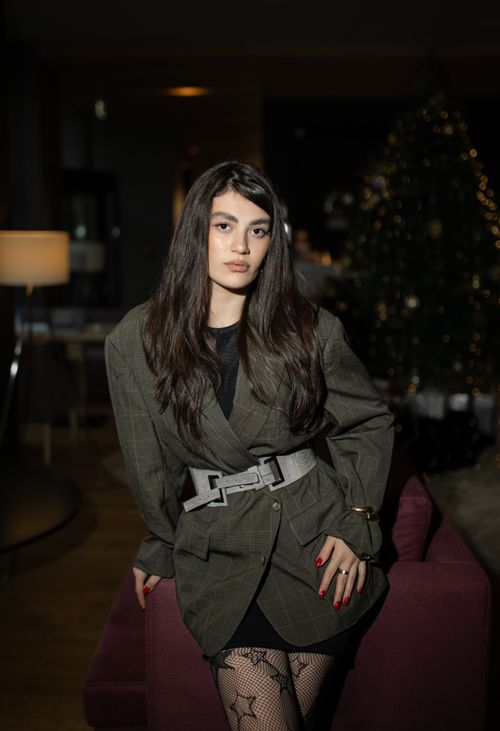 Free Portrait of an elegant woman indoors, with festive decor in the background, exuding confidence and style. Stock Photo