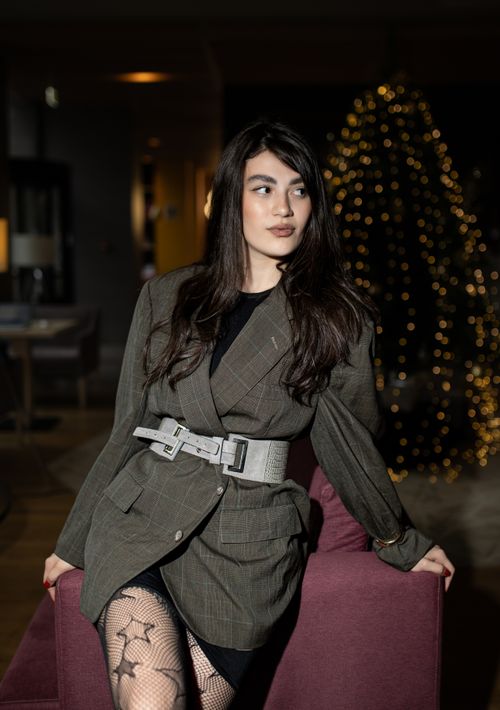 Free Stylish woman in blazer posing indoors with festive lights creating a warm atmosphere. Stock Photo