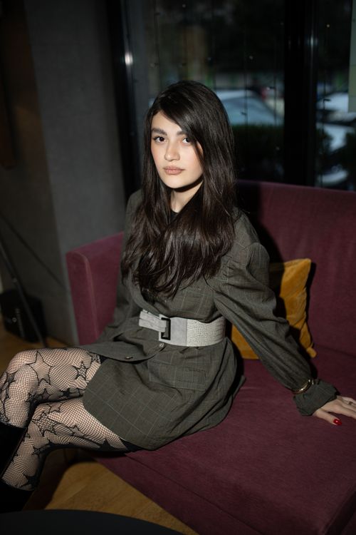 Free A stylish portrait of a young woman in fashionable attire sitting indoors on a sofa. Stock Photo