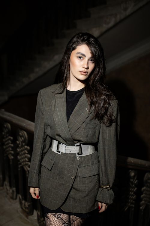 Free Elegant portrait of a woman in a blazer standing on a staircase. Stock Photo