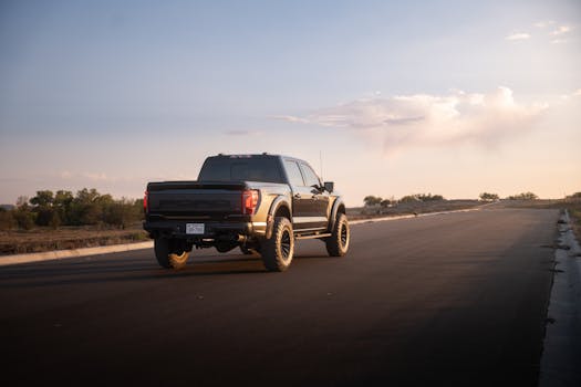 A black truck driving on an empty desert road during sunset, showcasing adventure and freedom.