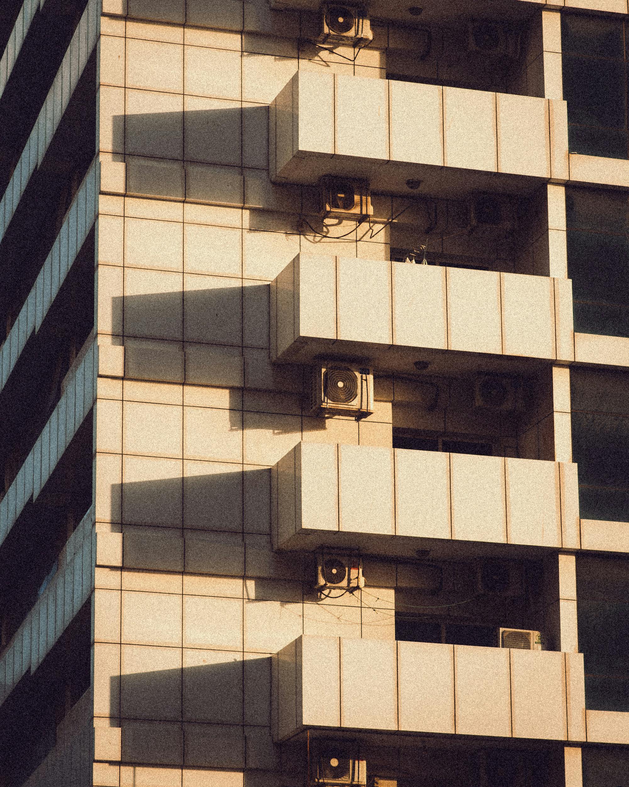 Close-up of a modern building facade casting geometric shadows with warm tones.
