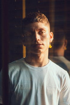 Young man with earrings in moody lighting indoors.