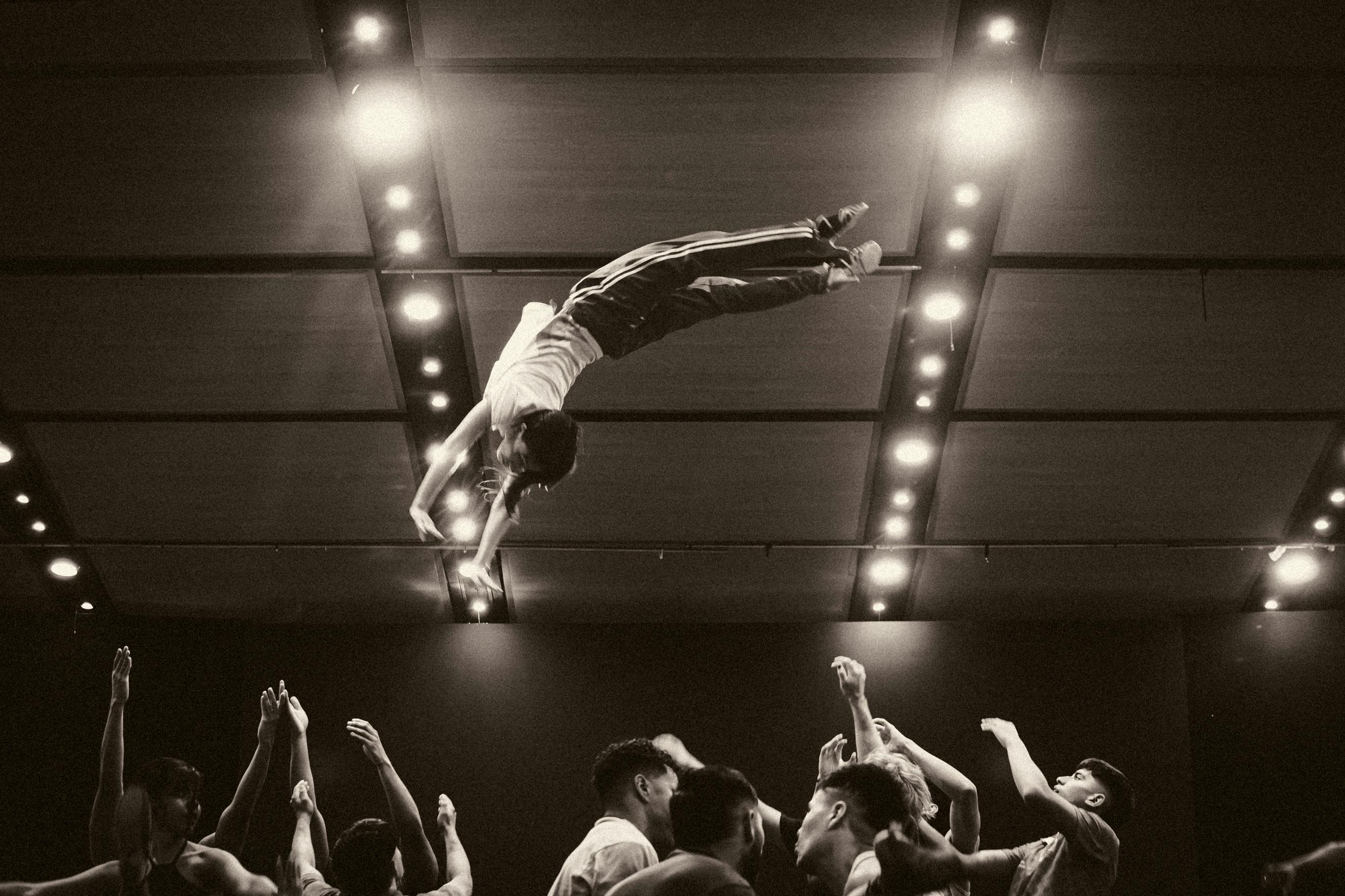 A stunning capture of a dancer mid-air leap in a dimly lit concert hall.