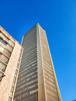 A striking modern skyscraper reaches upwards against a vivid blue sky, showcasing urban architecture.