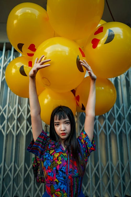 Woman Wearing Blue Top Standing in Front of Yellow Balloons
