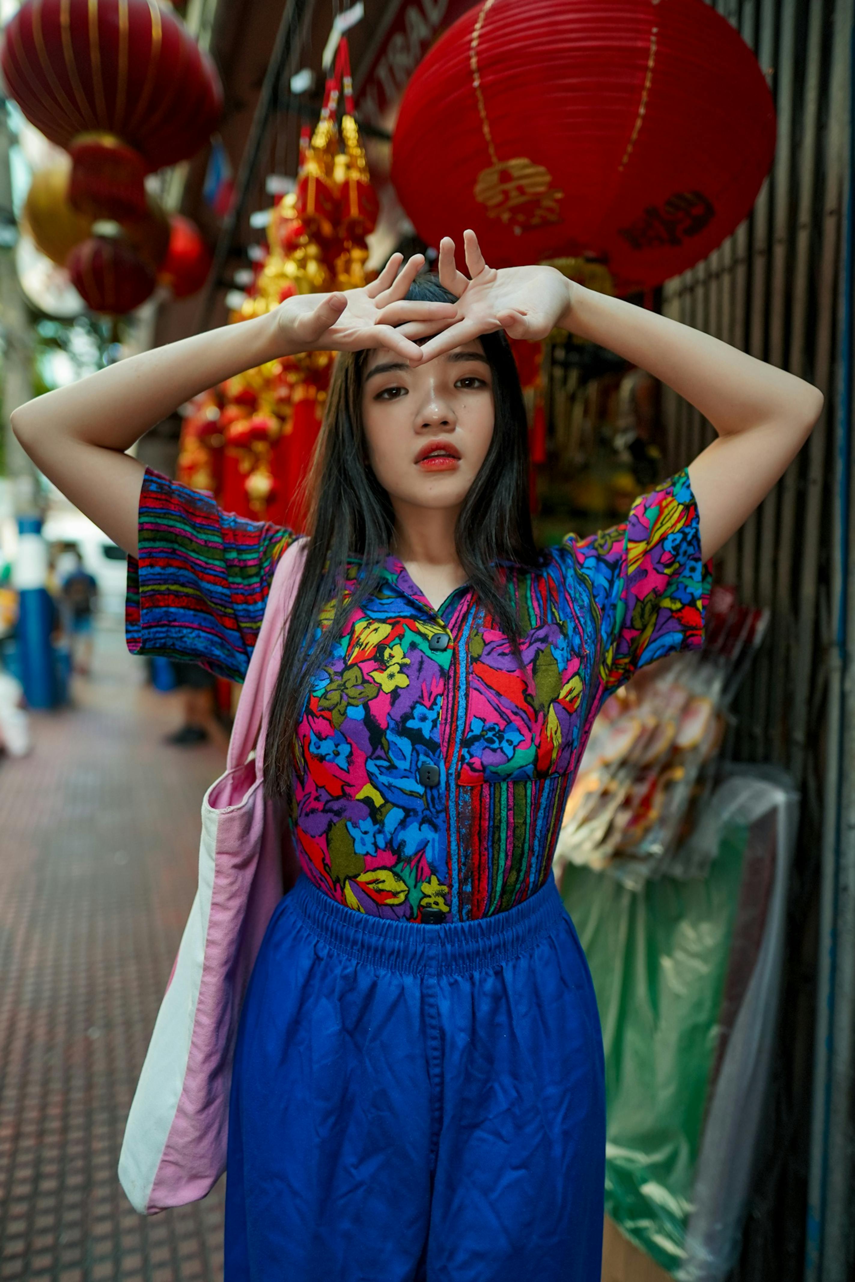 一位亚洲女子身着充满活力的服装，在繁华的城市街道上时尚地摆着姿势