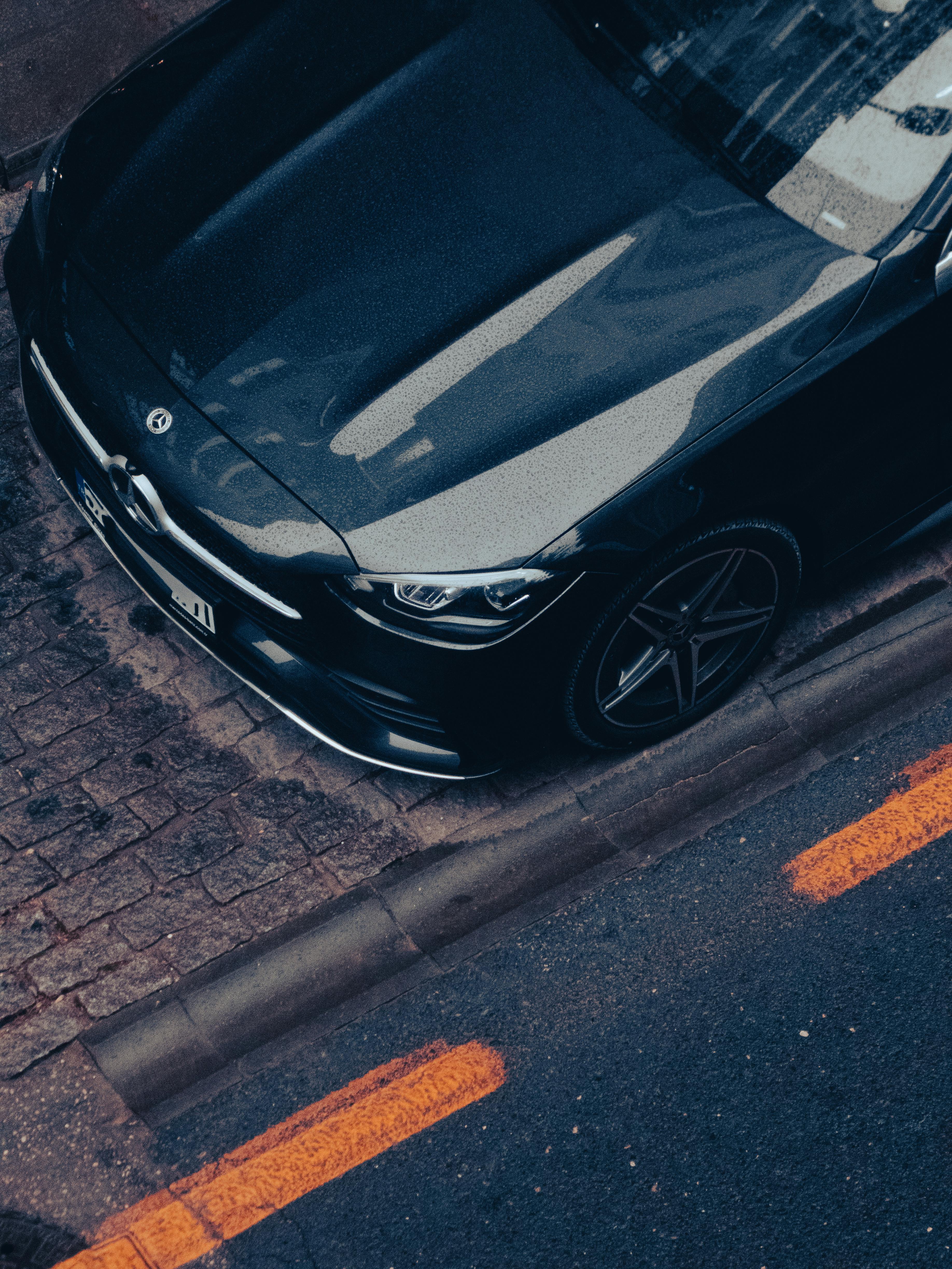Overhead shot of a luxury black car parked with reflection and urban vibe.