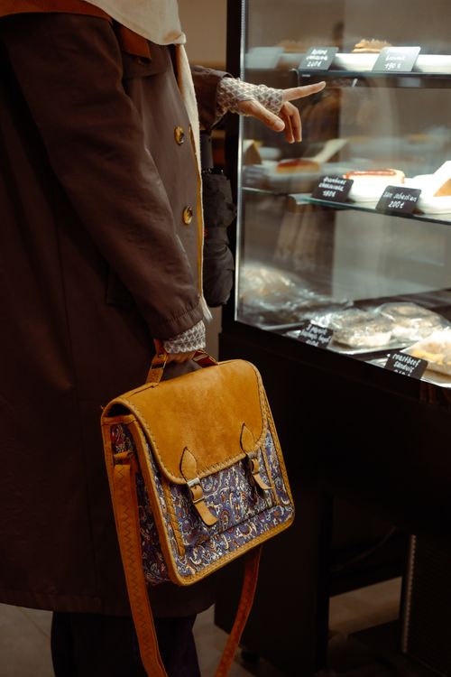 Free A person with a vintage handbag choosing desserts from a bakery display in Istanbul. Stock Photo
