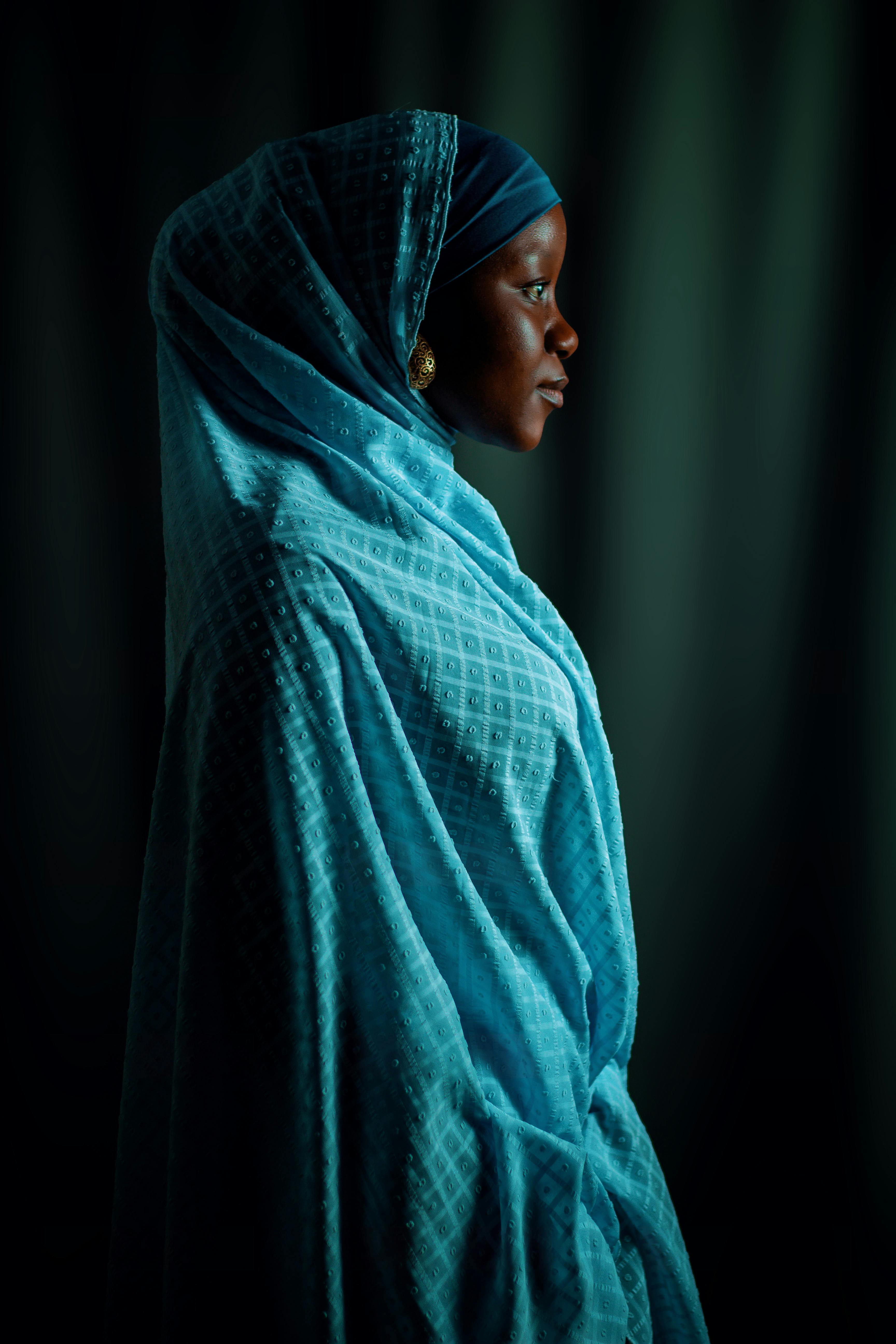 Side profile portrait of a woman in a blue hijab, serene and elegant.
