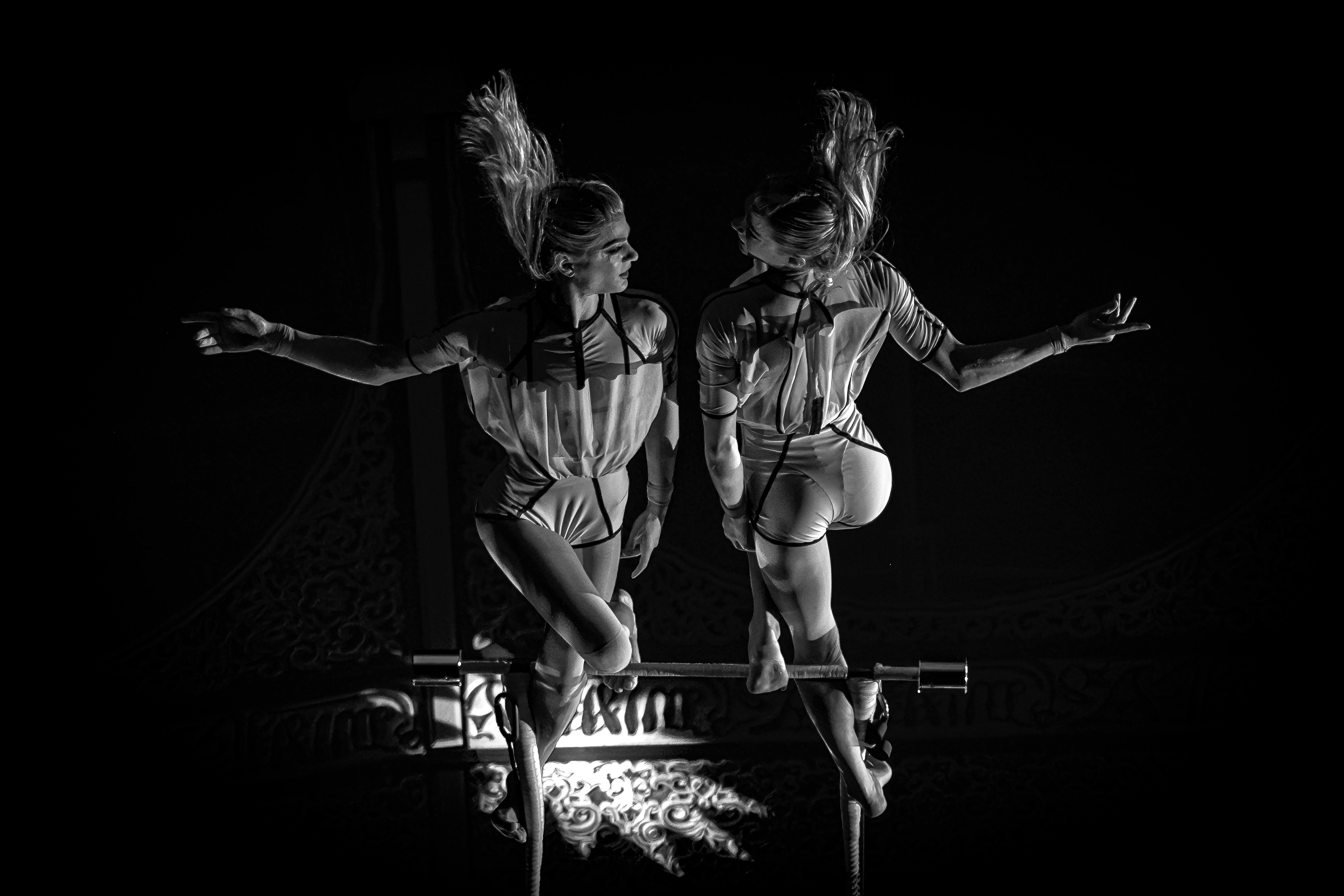 бесплатная Два акробата грациозно балансируют на канатах на фоне эффектной черно-белой декорации. Стоковое фото