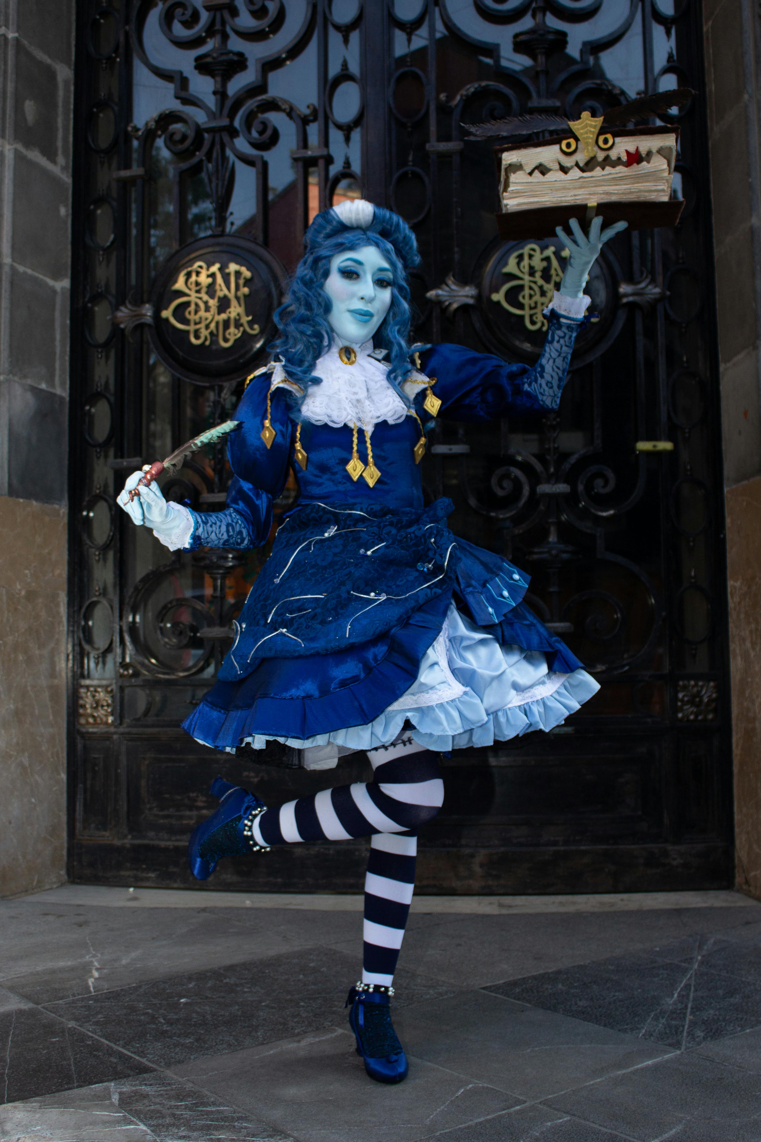 Ücretsiz Canlı mavi bir cosplay kostümü giymiş bir kişi, süslü bir kapının önünde zarif bir poz veriyor. Stok Fotoğraflar