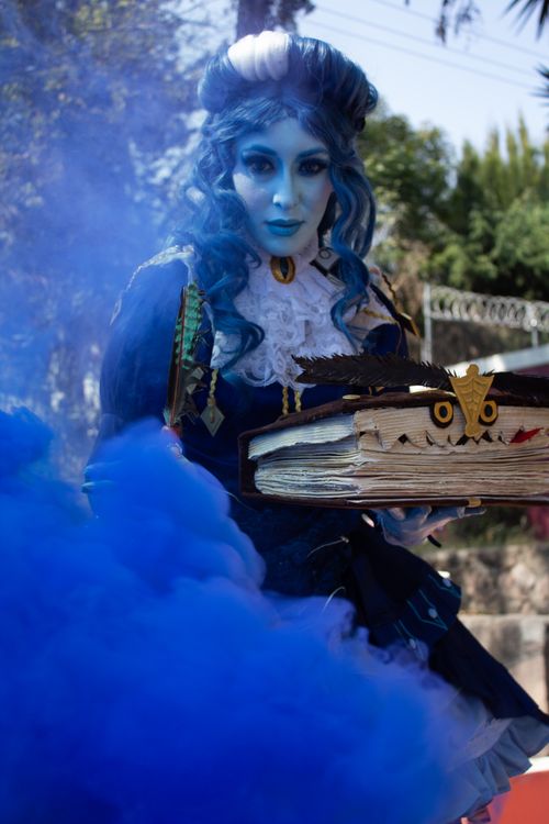 Free A captivating fantasy cosplay character with blue smoke and mystical book outdoors. Stock Photo
