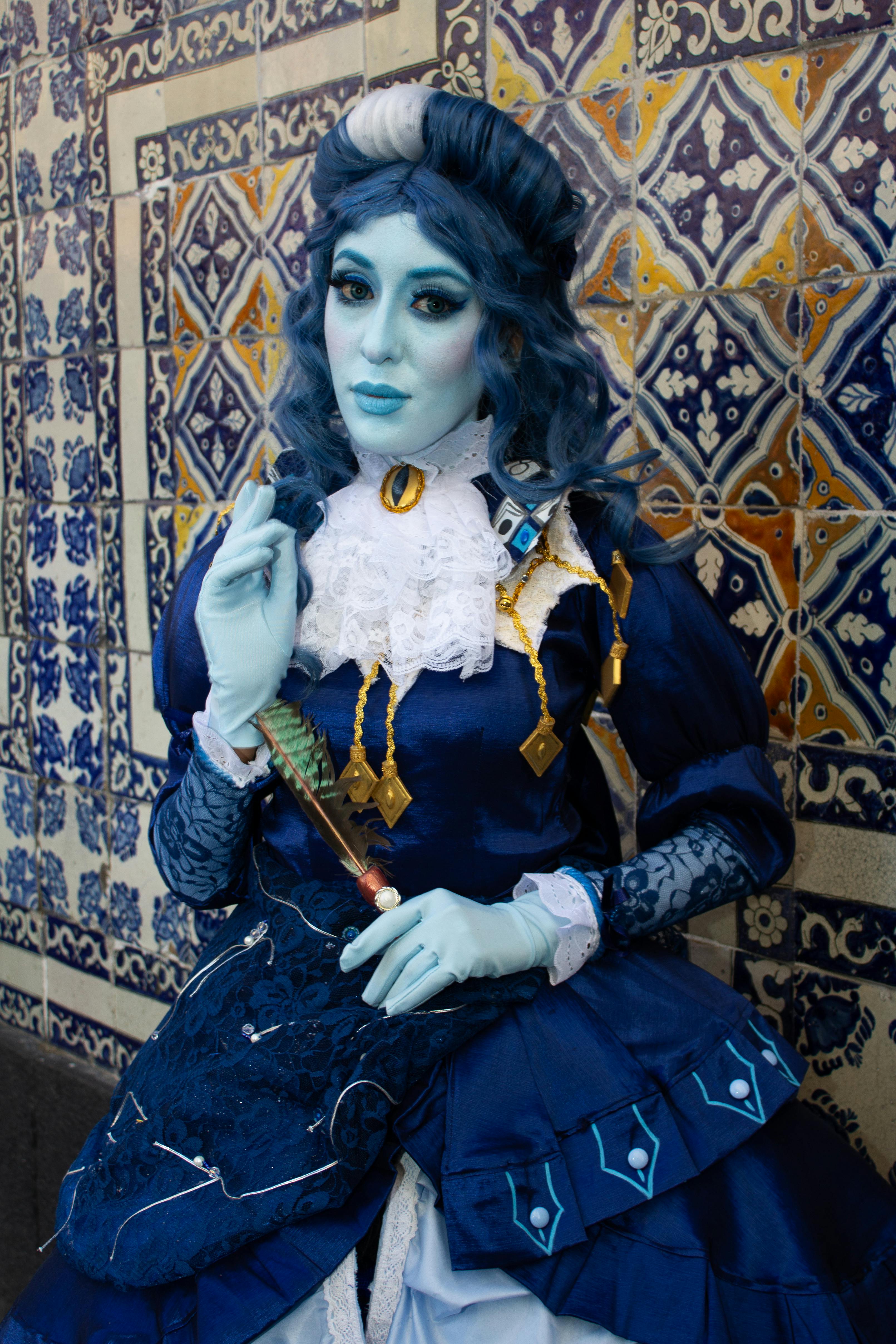 Ücretsiz Dekoratif karo duvarın önünde, detaylı mavi fantezi kostümü giymiş bir kişi. Stok Fotoğraflar
