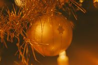 A festive golden Christmas ornament hangs amidst tinsel, capturing the holiday spirit.