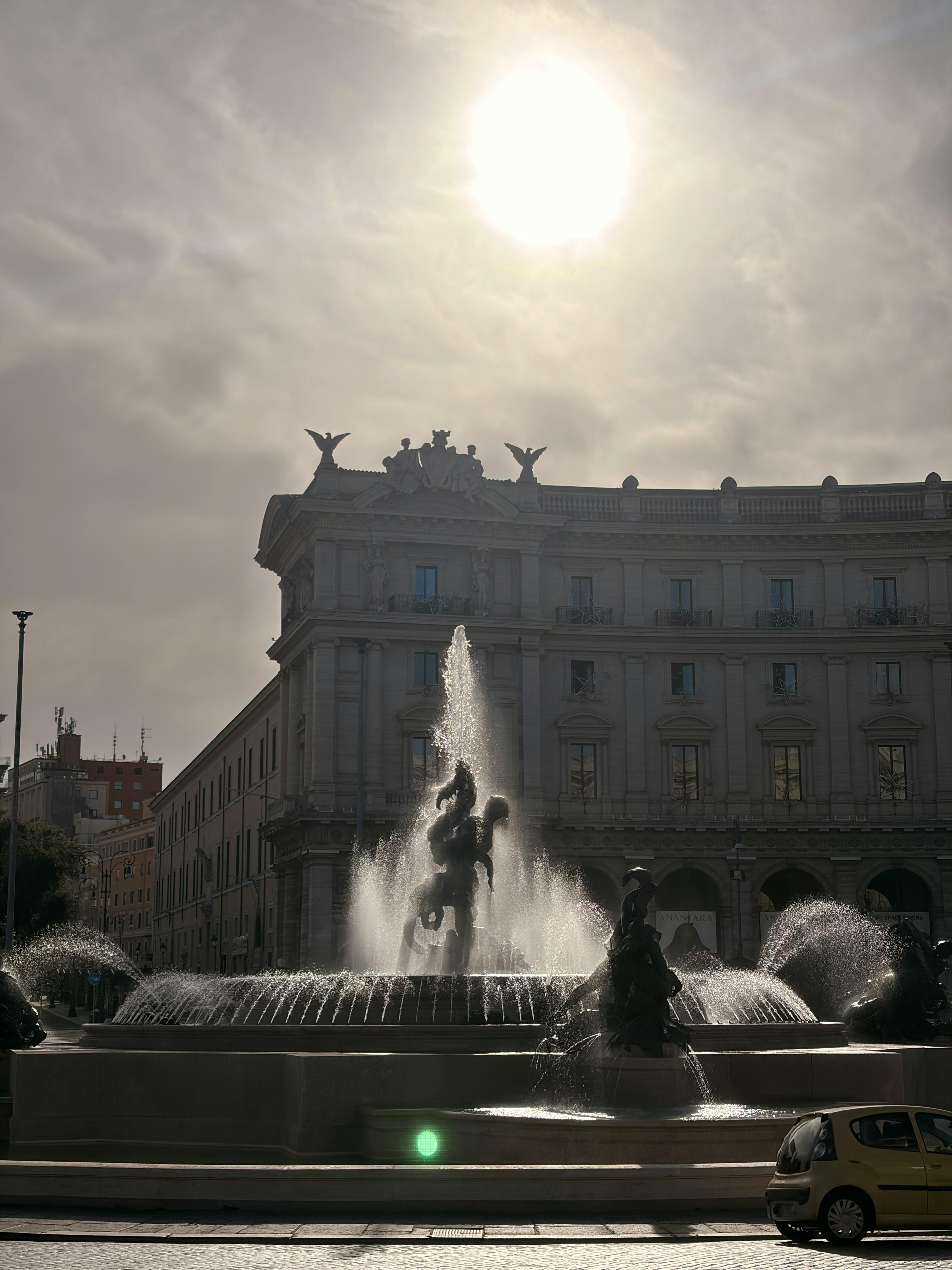 Fountain of Naiads in Piazza della Repubblica, Rome, under bright sun.