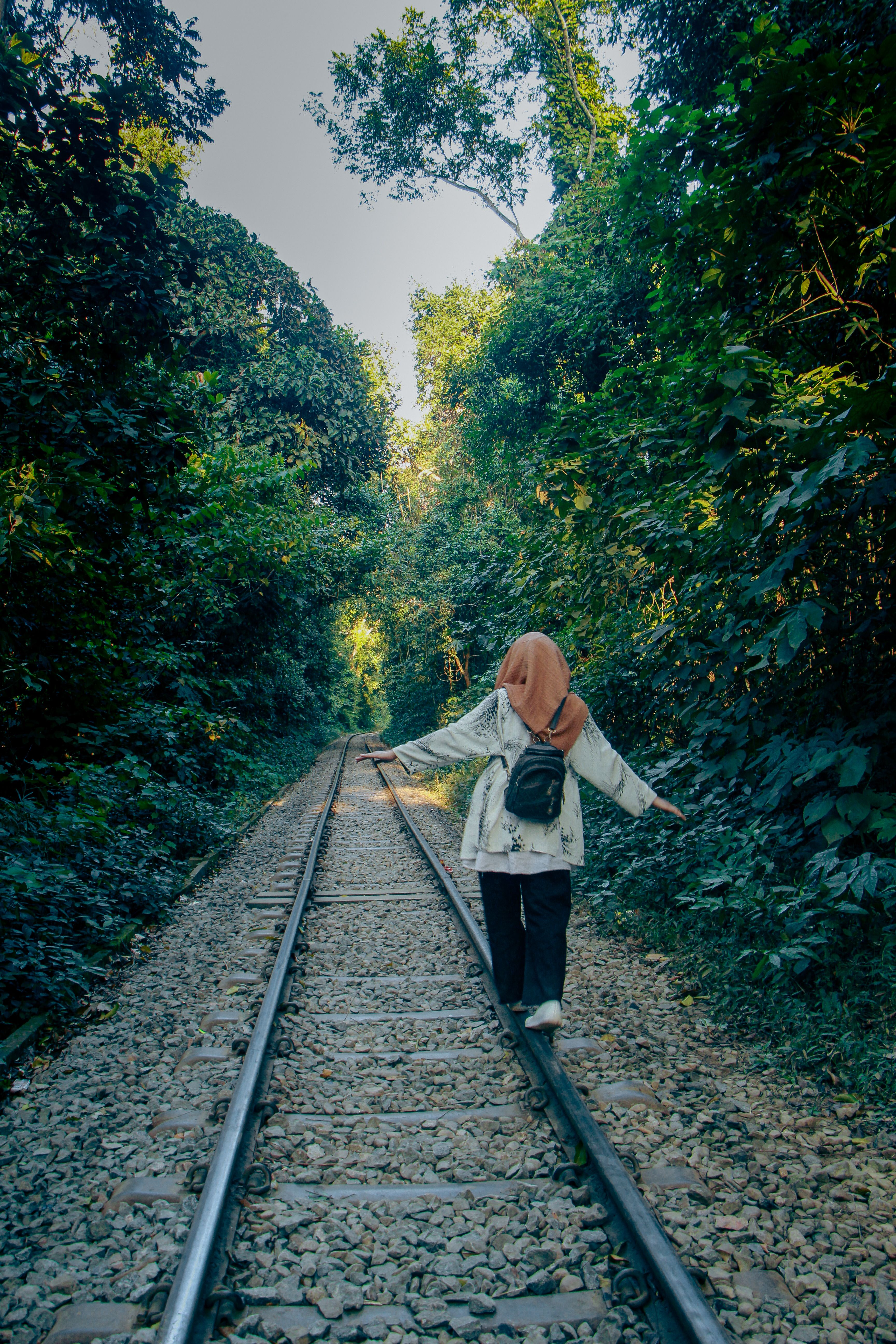 Woman Balancing on Railway Tracks in Lush Forest