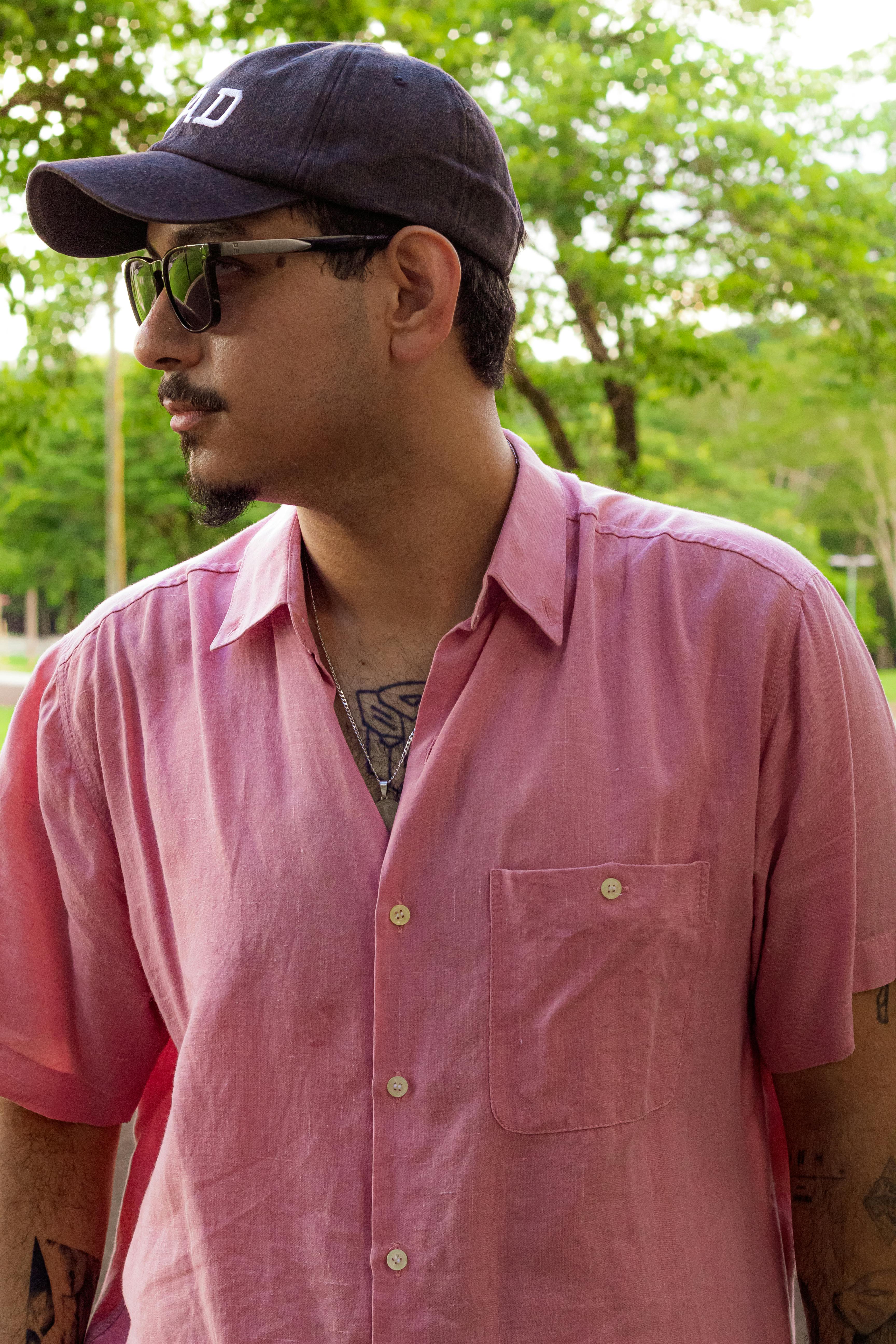 Man in pink shirt and sunglasses standing in a lush green park in Campo Grande, Brazil.