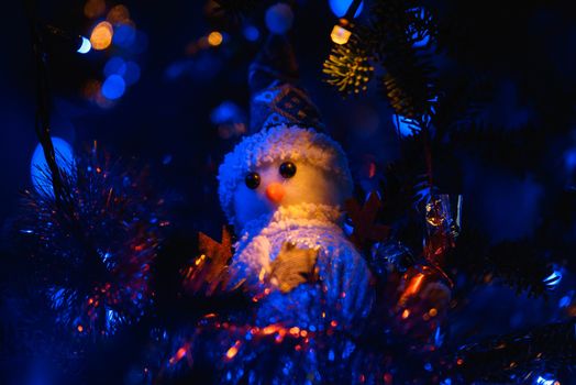 Festive blue lit snowman ornament nestled in a decorated Christmas tree, capturing holiday cheer and ambient lighting.