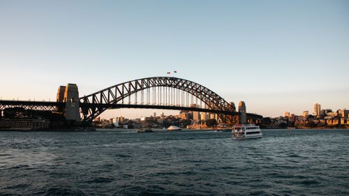 Free Sydney Harbour Bridge at sunset with ferry and city skyline in the background. Stock Photo