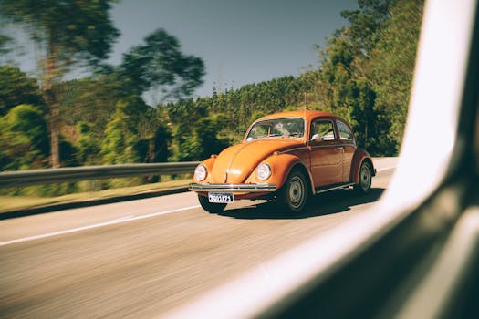 A classic orange Beetle car cruising on a scenic highway, capturing the essence of vintage travel.