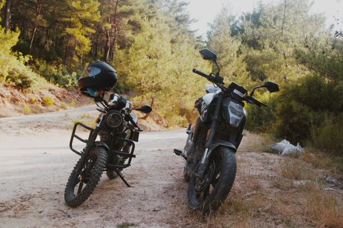 Free Two motorcycles parked on a dirt road in İzmir surrounded by lush forest. Stock Photo
