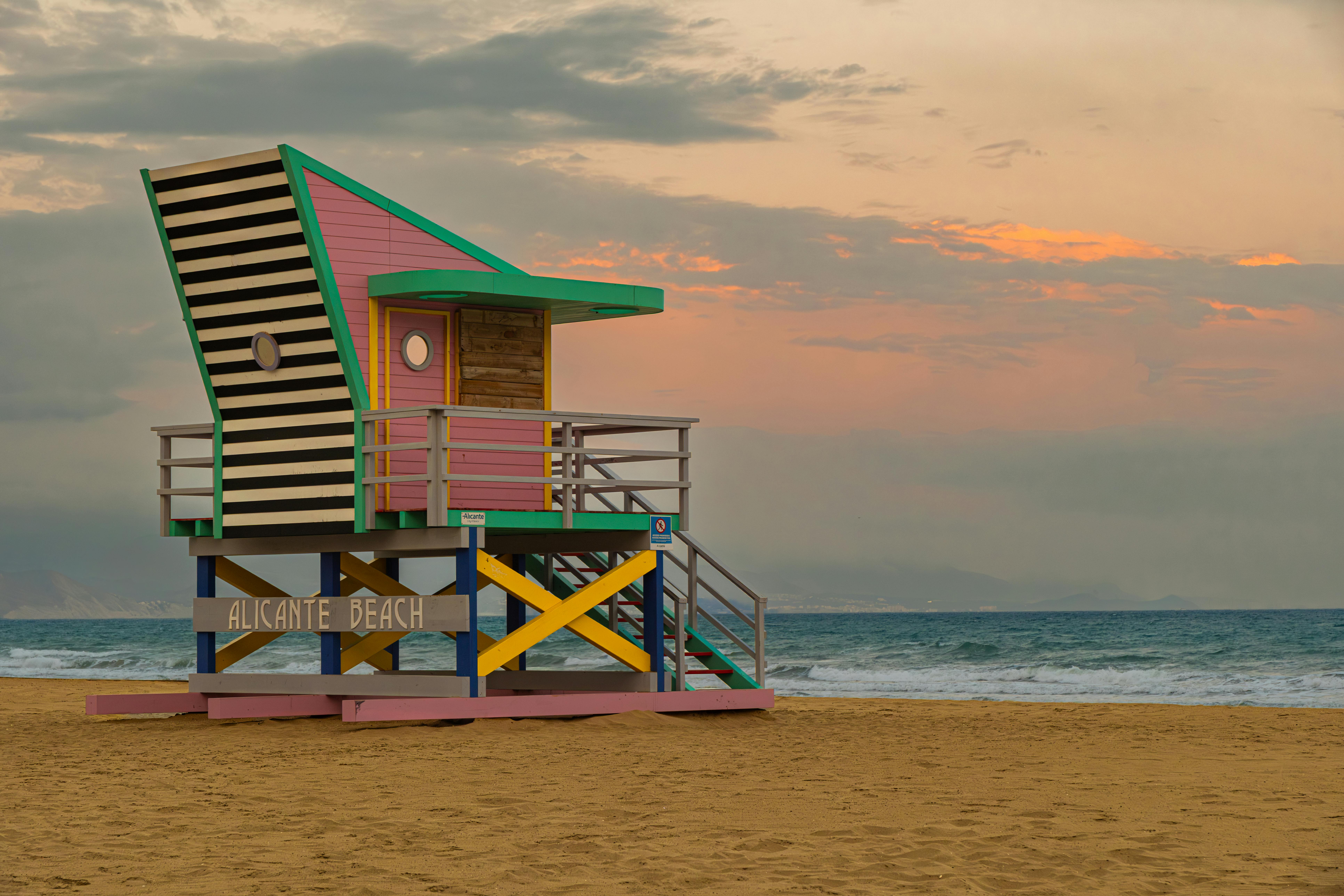 Vibrant lifeguard tower at sunset on Alicante Beach, Spain, showcasing unique architecture.
