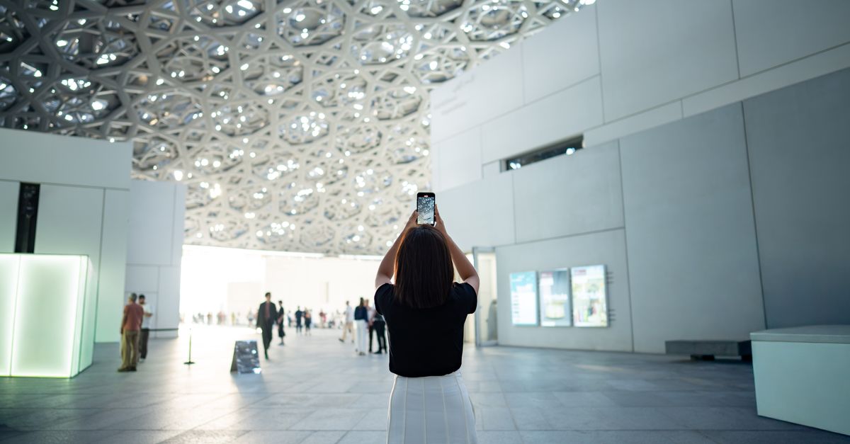 A visitor takes a photo of the intricate ceiling design at the Louvre Abu Dhabi, showcasing modern a