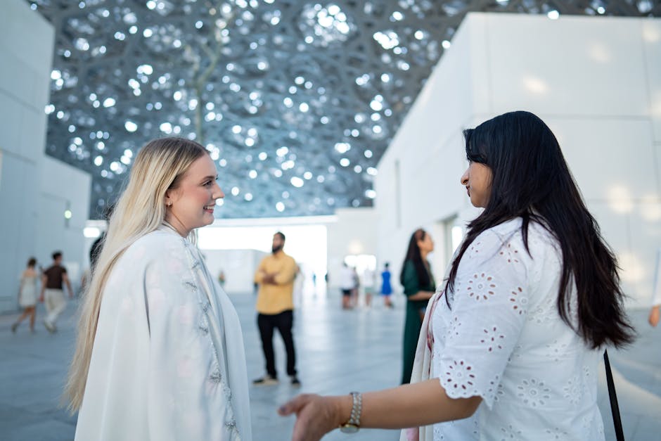 A candid shot of two women having a conversation inside a contemporary museum setting.