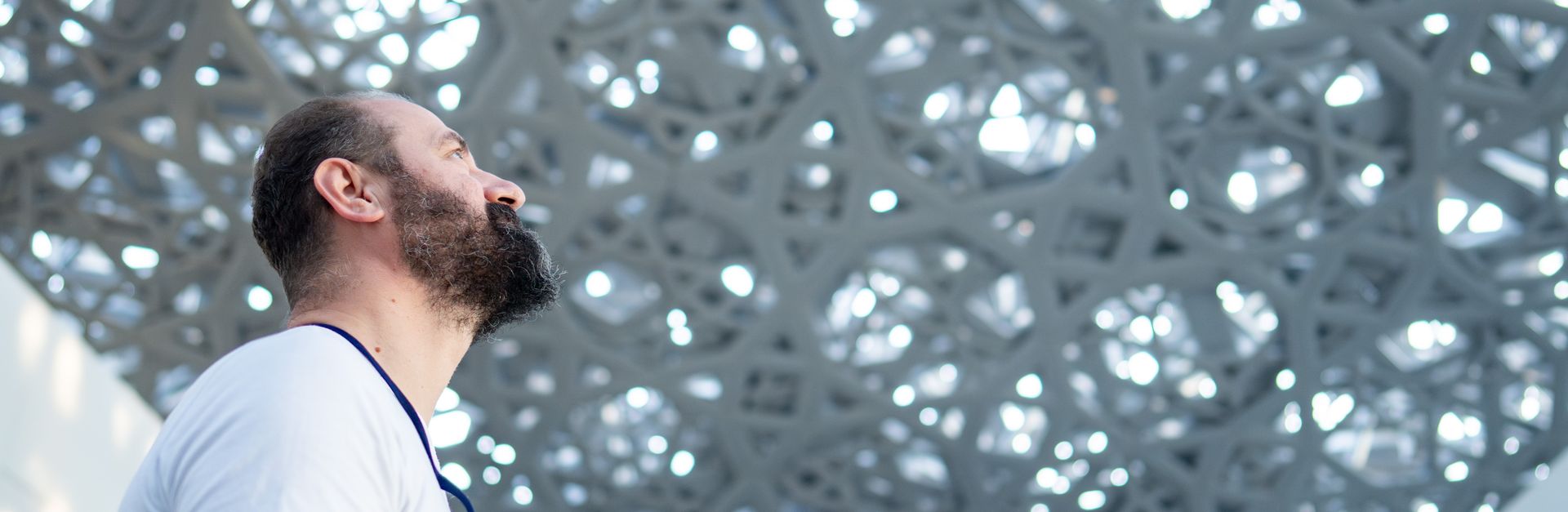A man admiring the intricate ceiling design of a modern museum indoors.