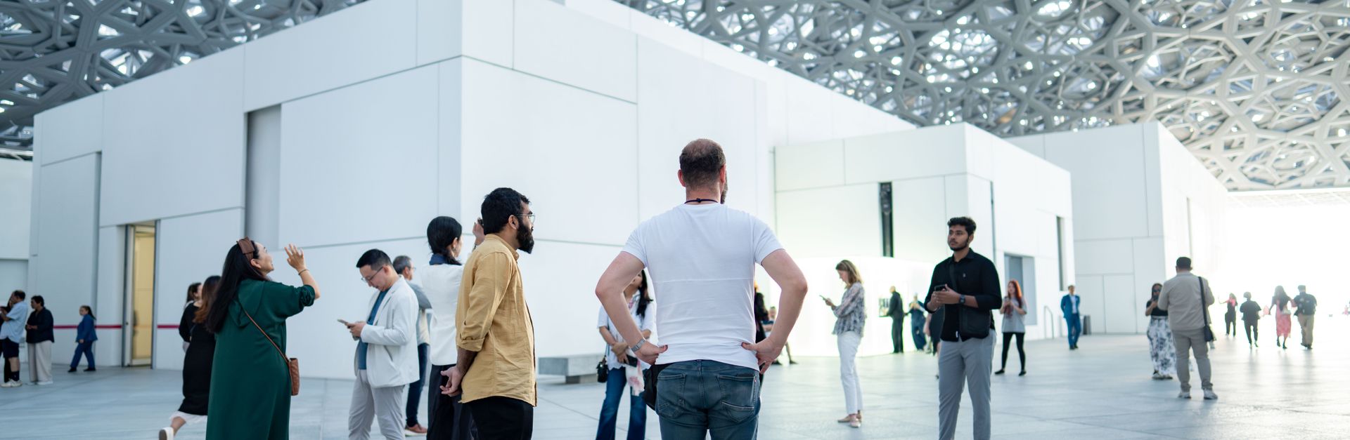 People exploring the atrium of Louvre Abu Dhabi under its unique architectural dome.