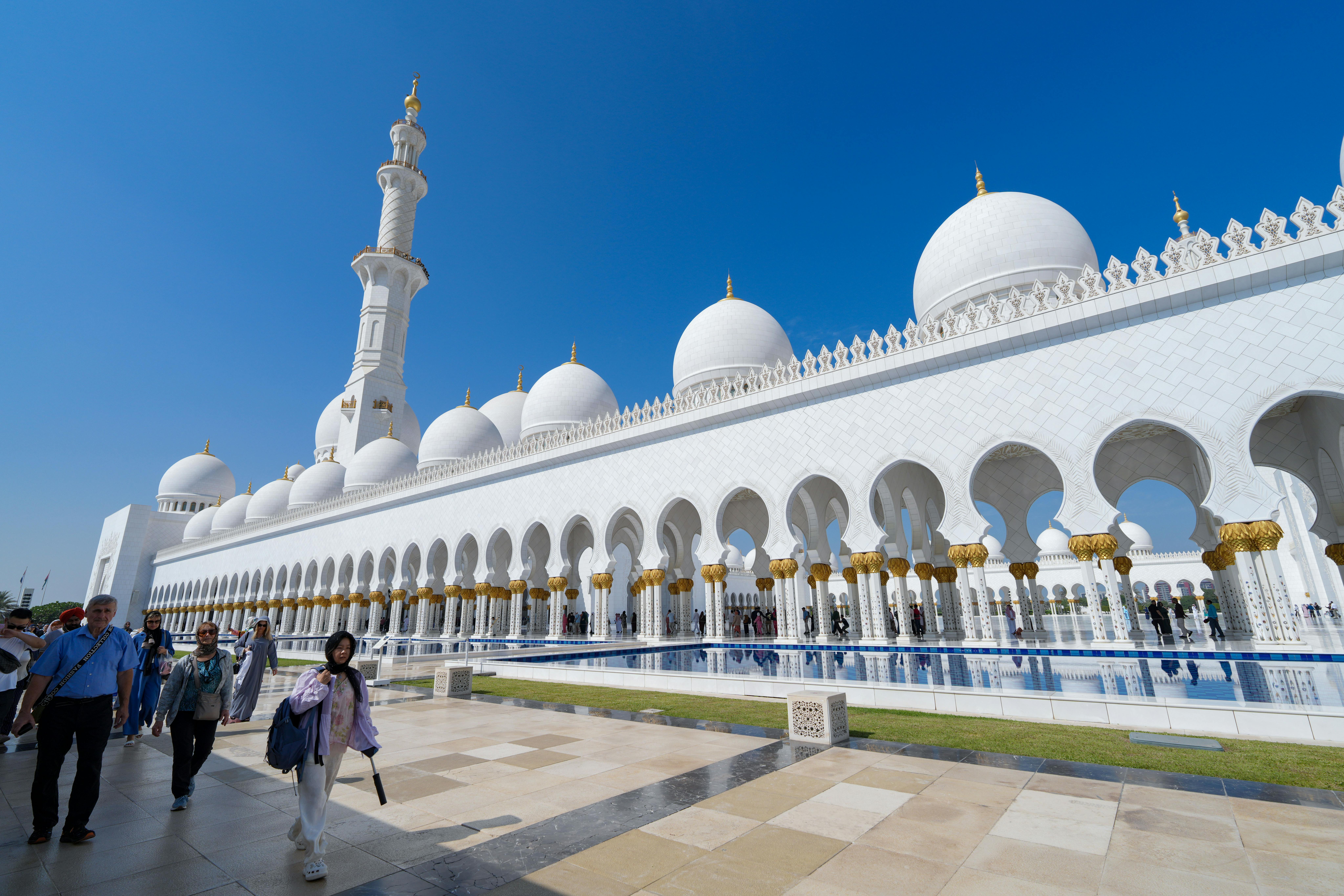Visitors at Sheikh Zayed Grand Mosque in Abu Dhabi marvel at its stunning white domes and architectu