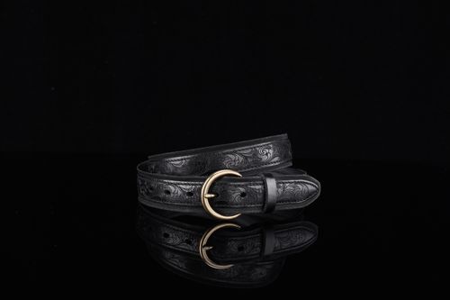 Free Stylish black leather belt with intricate embossing and brass buckle on black background. Stock Photo