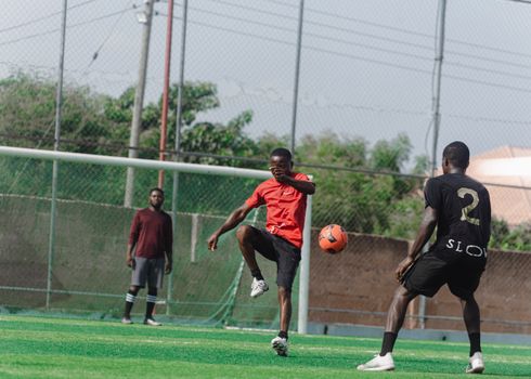 Three men playing soccer outdoors on a sunny day, showcasing teamwork and athleticism.