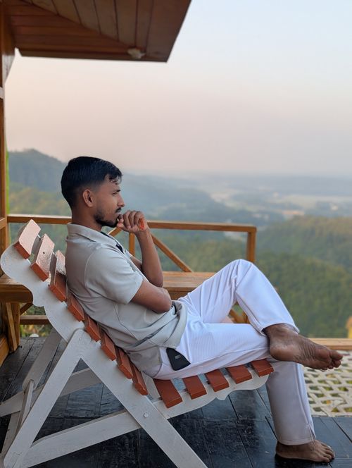 Free Man in contemplative mood seated on a balcony overlooking scenic mountain vista. Stock Photo