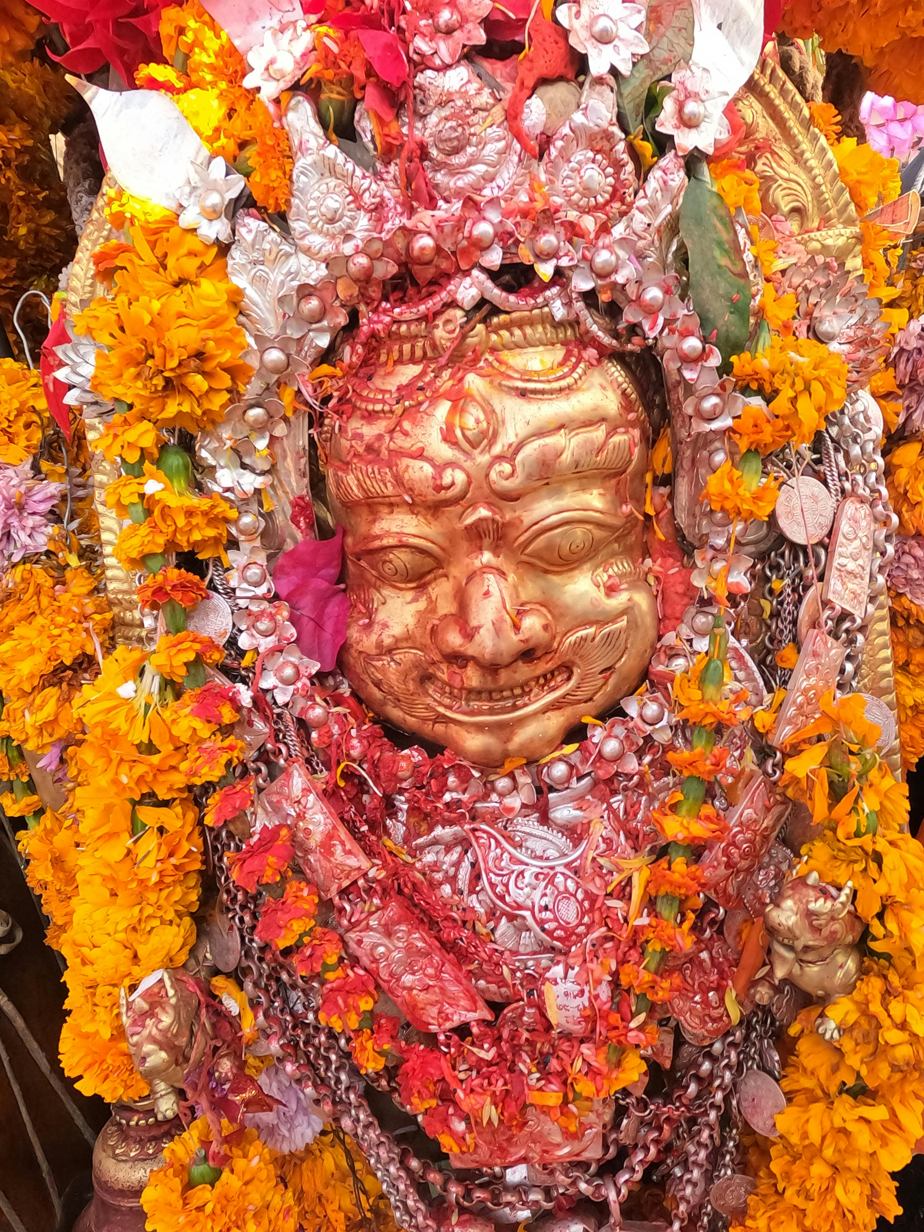 Intricate golden statue with marigold garlands, showcasing traditional religious artistry and craftsmanship.