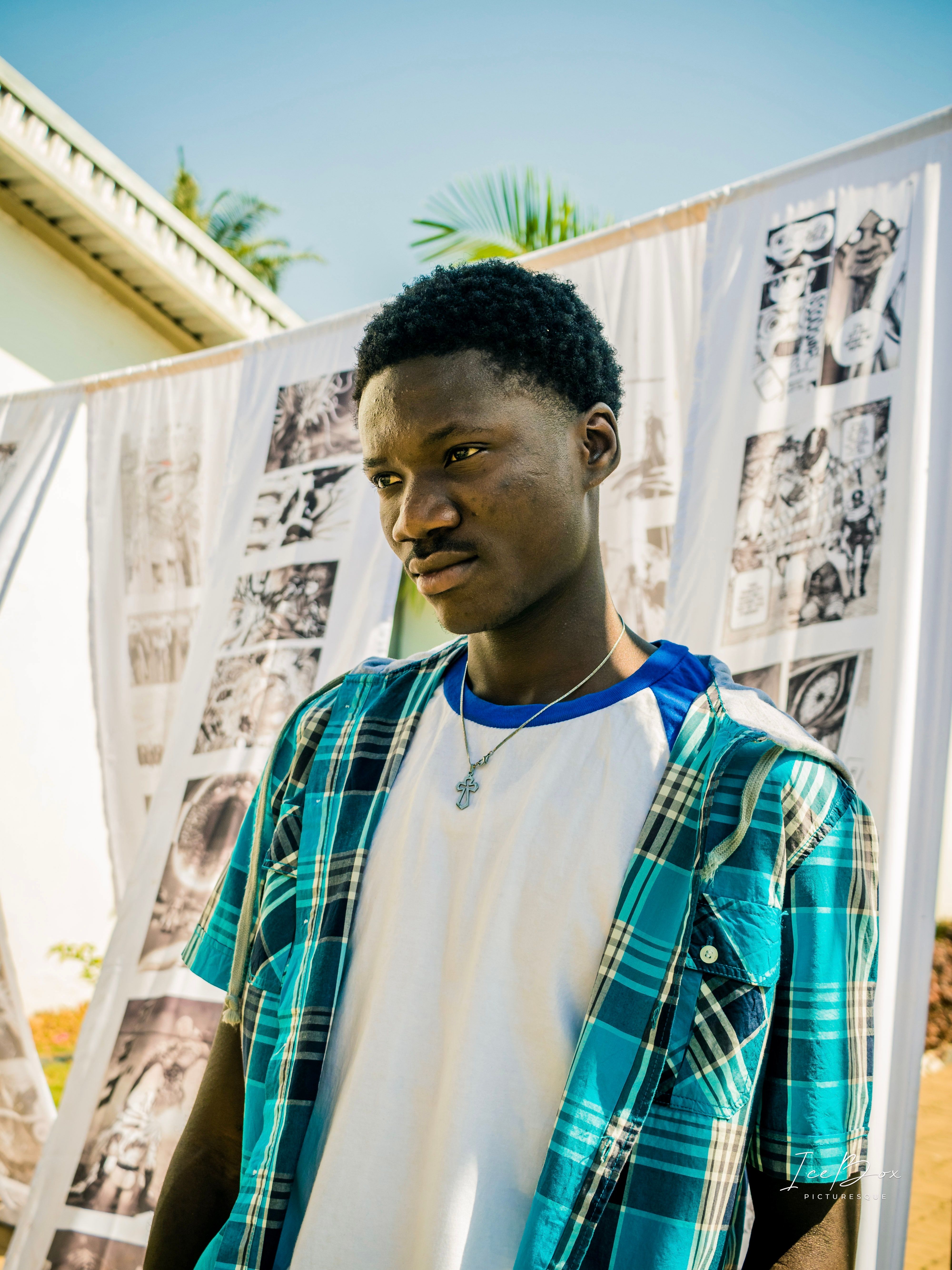Stylish portrait of a young man in a plaid shirt with outdoor backdrop, bright sunlight.